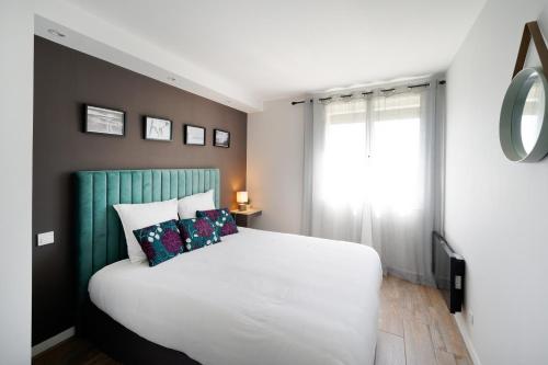 Un dormitorio con una cama blanca y una ventana. en Appart 12 pers 5km plage Hendaye, en Urrugne