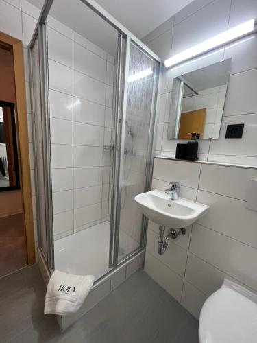 a bathroom with a shower and a sink and a toilet at Hotel HOLA in Stuttgart