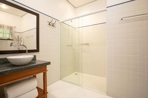 a bathroom with a sink and a glass shower at Porto Pacuíba Hotel in Ilhabela