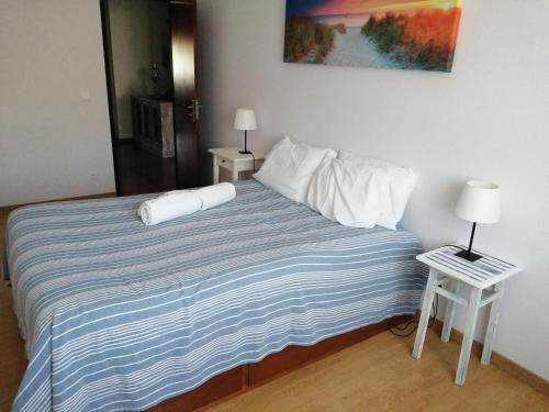 a bed with a blue and white striped blanket and two tables at Casa do Mar in Foz do Arelho