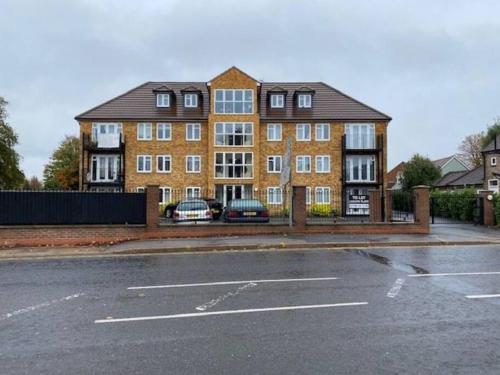 a large brick building with a parking lot in front of it at Large Luxury appartment in Cobham