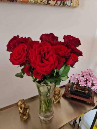 a vase filled with red roses sitting on a table at Large Luxury appartment in Cobham