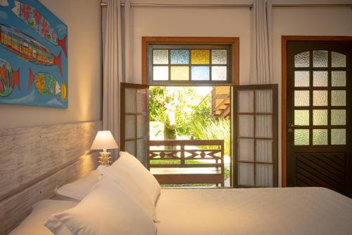 a bedroom with a bed and a window and a door at Porto Pacuíba Hotel in Ilhabela
