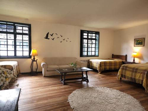 a living room with two beds and a couch and a table at Hacienda Suescún - 300 Años de Historia in Tibasosa