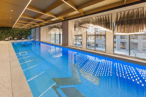 a large swimming pool with blue water in a building at Meriton Suites King Street Melbourne in Melbourne