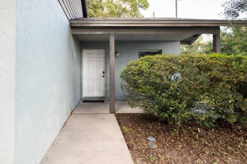 a white building with a white door and a bush at Cute downtown home by Depot Park in Gainesville