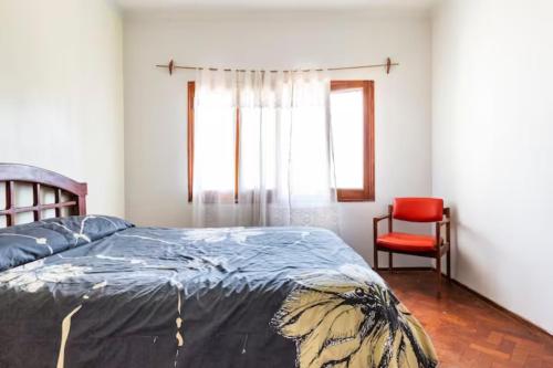 a bedroom with a bed and a red chair at La Juana Mza in Guaymallen