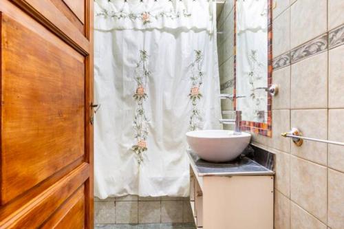 a bathroom with a sink and a white shower curtain at La Juana Mza in Guaymallen