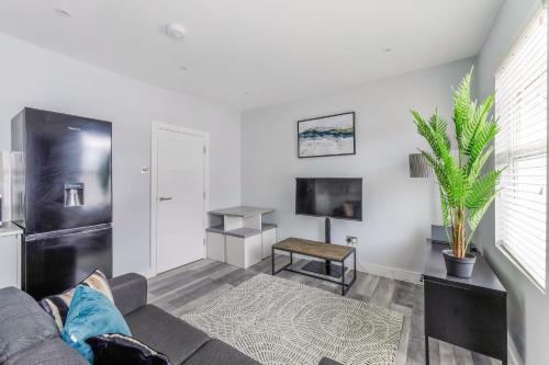 een woonkamer met een bank en een tv bij Elegant Croydon Apartment in Londen