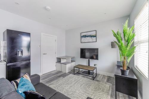 een woonkamer met een bank en een tv bij Elegant Croydon Apartment - Central location - Easy access to London Bridge and Gatwick Airport in Londen