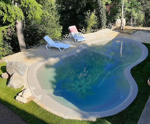 a swimming pool with two lawn chairs and a poolvisorvisorangering at B&B Cal Torello in Urbino