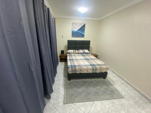 ein Schlafzimmer mit einem Bett in einem Zimmer mit Vorhängen in der Unterkunft 3XN Homes in Taifa