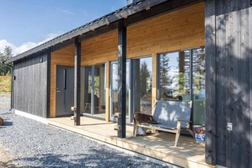 una casa con finestre di vetro e un divano su una veranda di Unique new cabin by Hafjell & Skei with stunning view a Tretten
