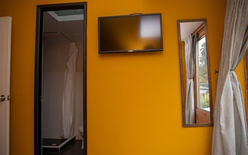baño con pared amarilla y TV en la pared en Hotel Valjala, en Manizales