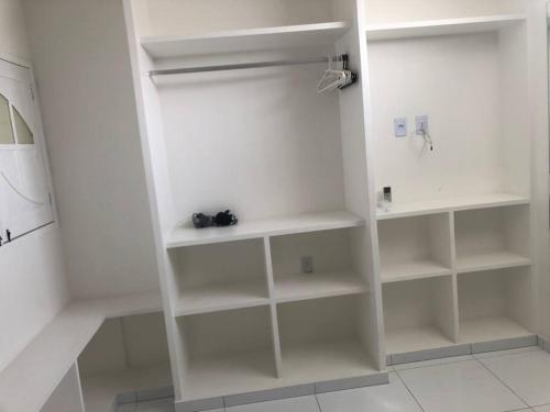 einen weißen Schrank mit weißen Regalen in einem Zimmer in der Unterkunft CASA PARA TEMPORADA CAMPINA GRANDE! in Campina Grande