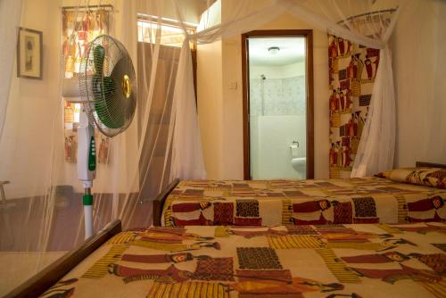 a bedroom with a bed and a fan at Bwana Tembo Safari Camp in Paraa