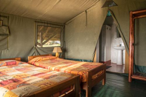 een slaapkamer met 2 bedden en een wastafel bij Bwana Tembo Safari Camp in Paraa