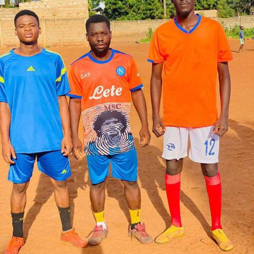 trois hommes debout côte à côte sur un terrain de football dans l'établissement Agoe, à Lomé