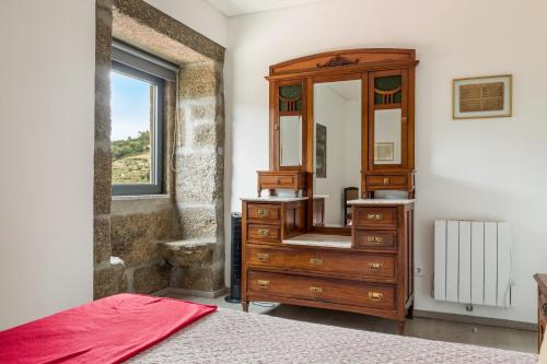 a bedroom with a wooden dresser and a mirror at Quinta Barqueiros D'Ouro - Casa da Música in Mesão Frio