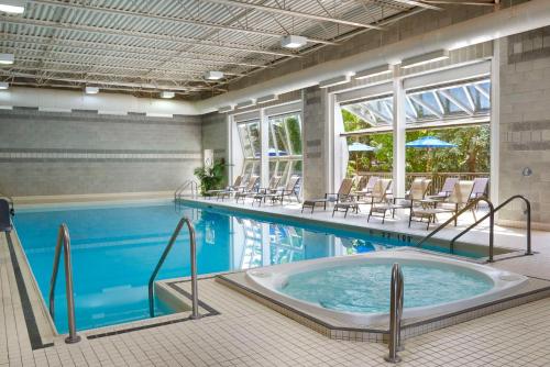 een groot zwembad met stoelen en een hot tub bij Best Western Parkway Hotel Toronto North in Richmond Hill