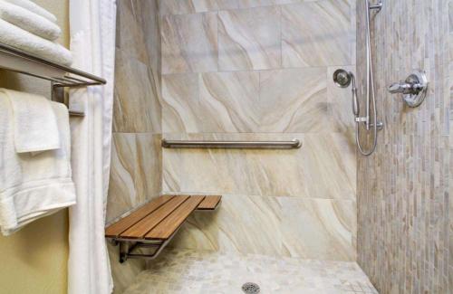 eine Dusche mit einer Holzbank im Bad in der Unterkunft Best Western Eagles Inn in Morehead
