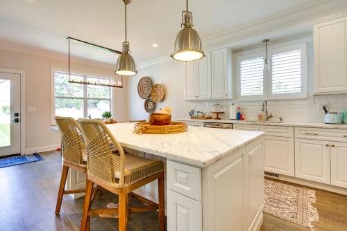 a kitchen with white cabinets and a island with chairs at Sleek Long Branch Vacation Rental with Yard and Patio! in Long Branch