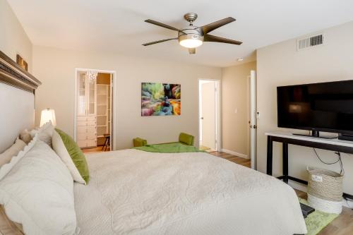 a bedroom with a white bed and a flat screen tv at Golf Course, Pool Access Palm Desert Condo! in Palm Desert
