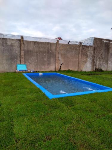 an empty swimming pool in the grass next to a wall at Family Place II in Luján