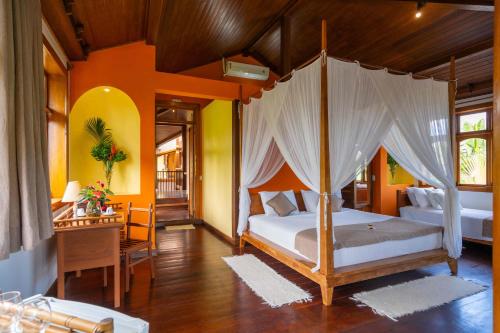 a bedroom with a canopy bed and a desk at Sagui Boutique Hotel in Arraial d'Ajuda