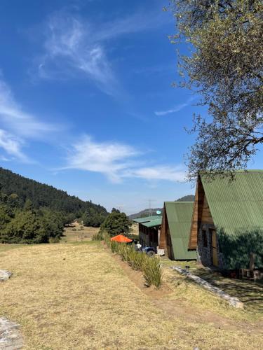 una granja con dos edificios y un campo de césped en Bosque de Perlillas, en Ciudad de México