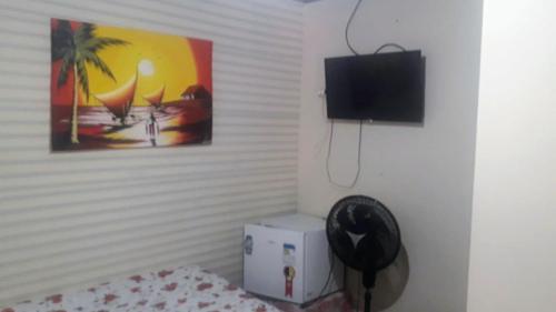 a room with a bed and a tv on a wall at Pousada Tia Tina in Paranaguá