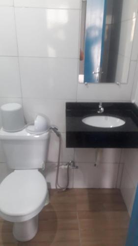 a bathroom with a white toilet and a sink at Pousada Tia Tina in Paranaguá