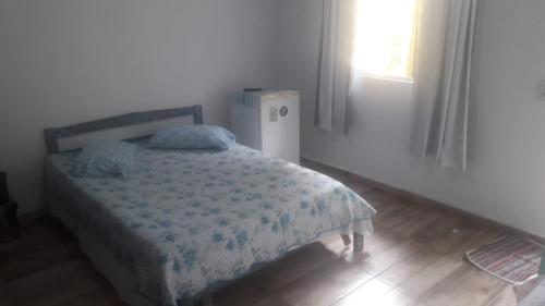 1 dormitorio con 1 cama, ventana y nevera en Pousada Tia Tina, en Paranaguá