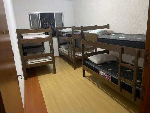 a room with three bunk beds and a wooden floor at Hostel Salus in Barueri