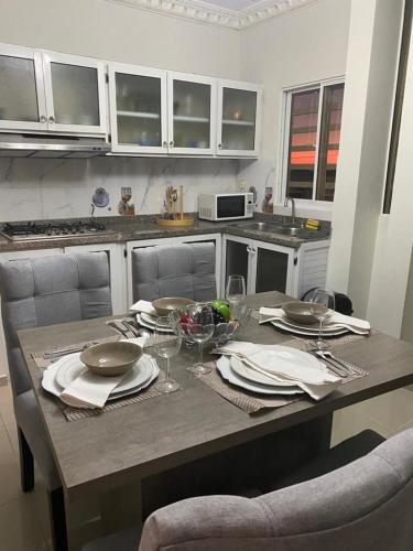 a kitchen with a table with plates and wine glasses at Pen House Vista Sur in Baní