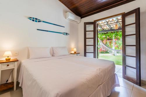 Un dormitorio con una gran cama blanca y una ventana en Vila Damai Maresias en Maresias