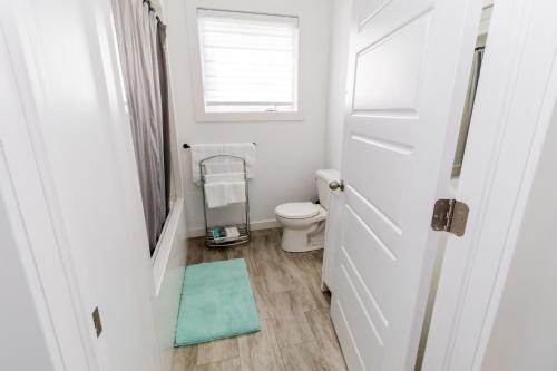 a bathroom with a toilet and a window and a door at The Apartment in Deer Lake