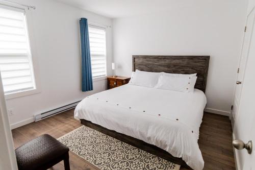 a bedroom with a large white bed and two windows at The Apartment in Deer Lake