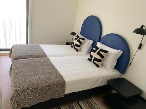 a bedroom with a bed with a blue headboard and pillows at Leça Apartments in Leça da Palmeira