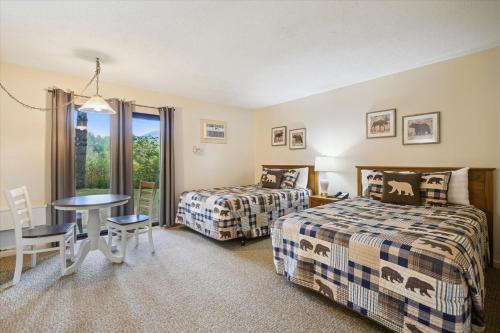 ein Hotelzimmer mit 2 Betten, einem Tisch und Stühlen in der Unterkunft Cedarbrook Deluxe Two Bedroom Suite, With heated pool 10102 in Killington