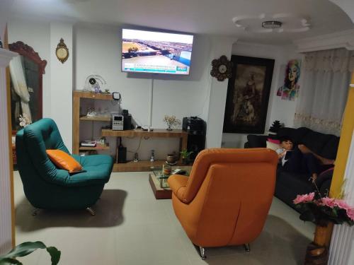 a living room with two chairs and a flat screen tv at La Pamela in Medellín
