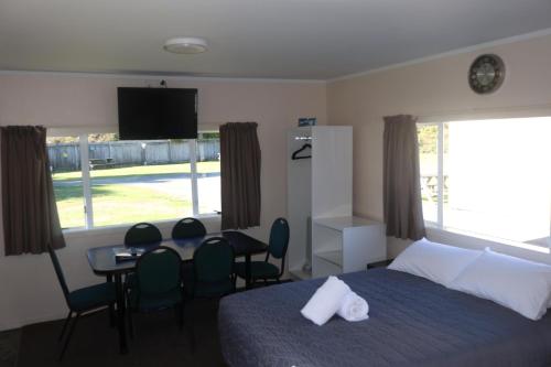 a bedroom with a bed and a table and chairs at Pohara Beach TOP 10 Holiday Park in Pohara