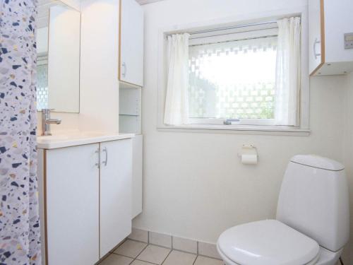 baño blanco con aseo y ventana en Two-Bedroom Holiday home in Lemvig 1, en Lemvig