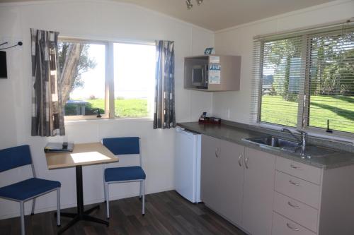 a kitchen with a sink and a table and chairs at Pohara Beach TOP 10 Holiday Park in Pohara