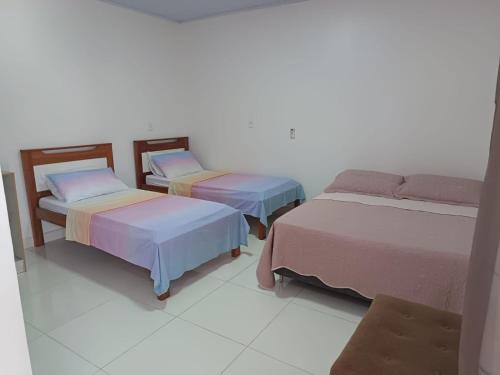 a room with three beds in a room at Pousada Muiraquitã Parintins in Parintins