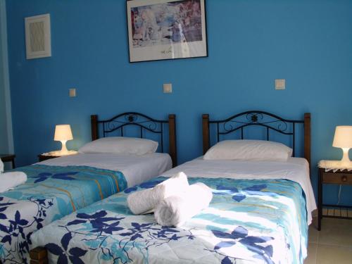 two beds in a room with blue walls at Villa Christine - Maisonettes with fireplace in Aliveri