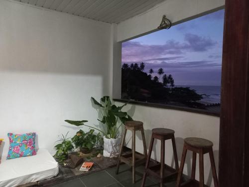 a room with stools and a window with a view of the ocean at LahSelva Pousada Hostel in Itacaré