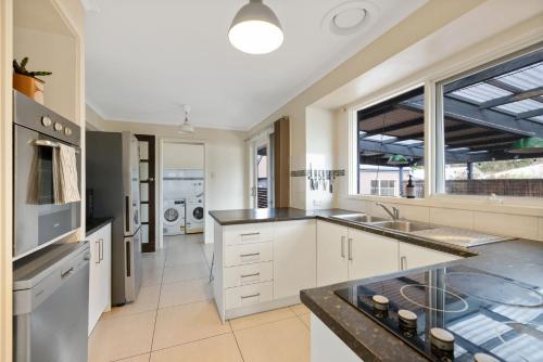 a large kitchen with white cabinets and a large window at Back Beach Oasis in Smiths Beach