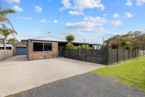 a house with a black fence and a driveway at Back Beach Oasis in Smiths Beach