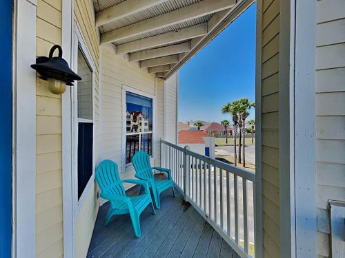 a porch with two blue chairs on a house at Toes In The Water II in Padre Island